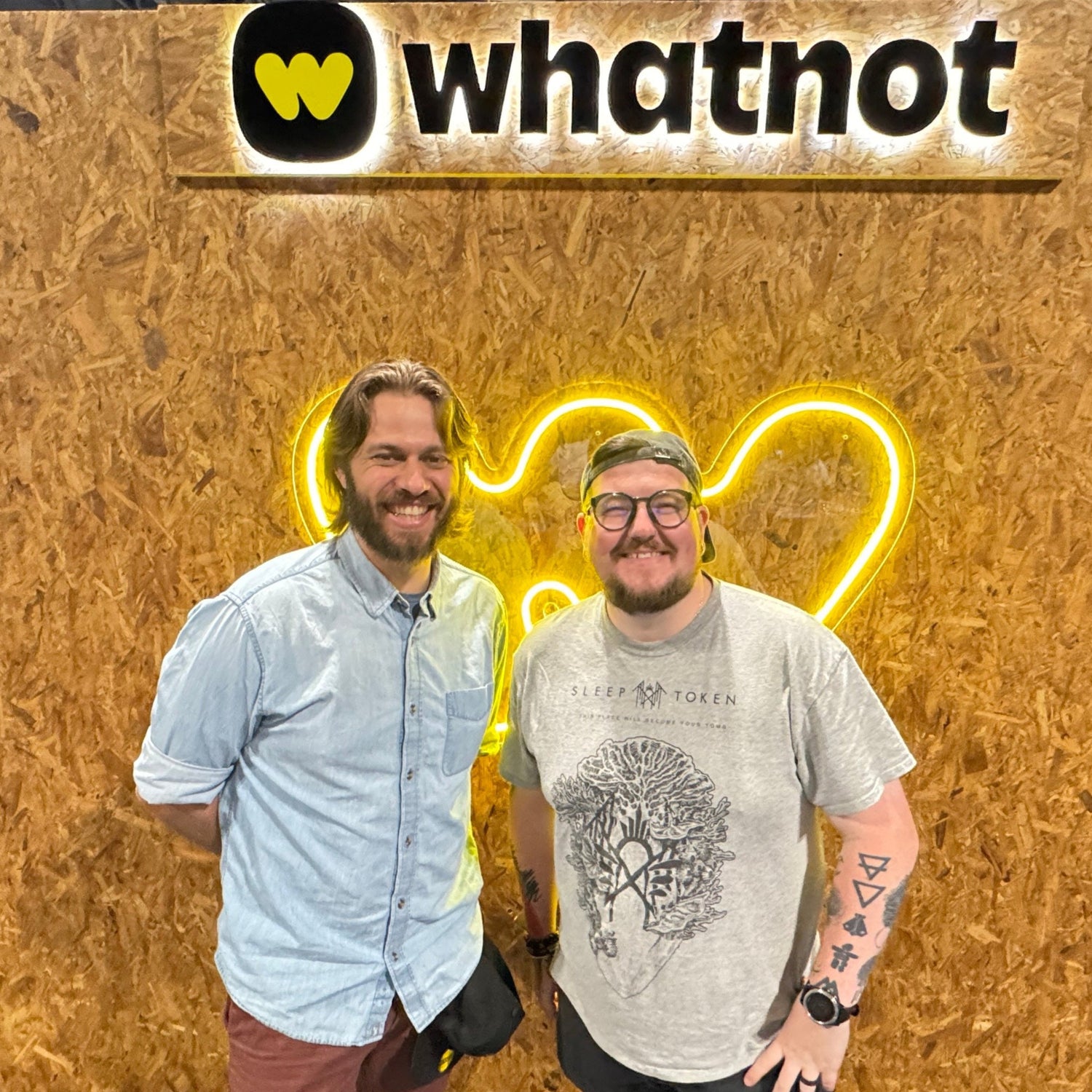 Two men posing in front of a wooden backdrop with 'whatnot' branding.